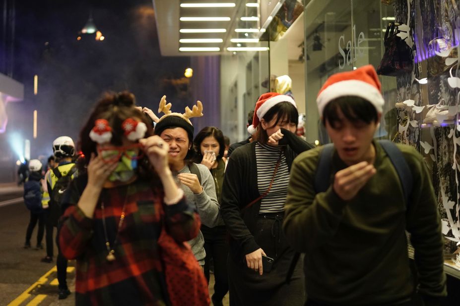 People celebrating the holidays react to tear gas as police confront protesters on Christmas Eve.