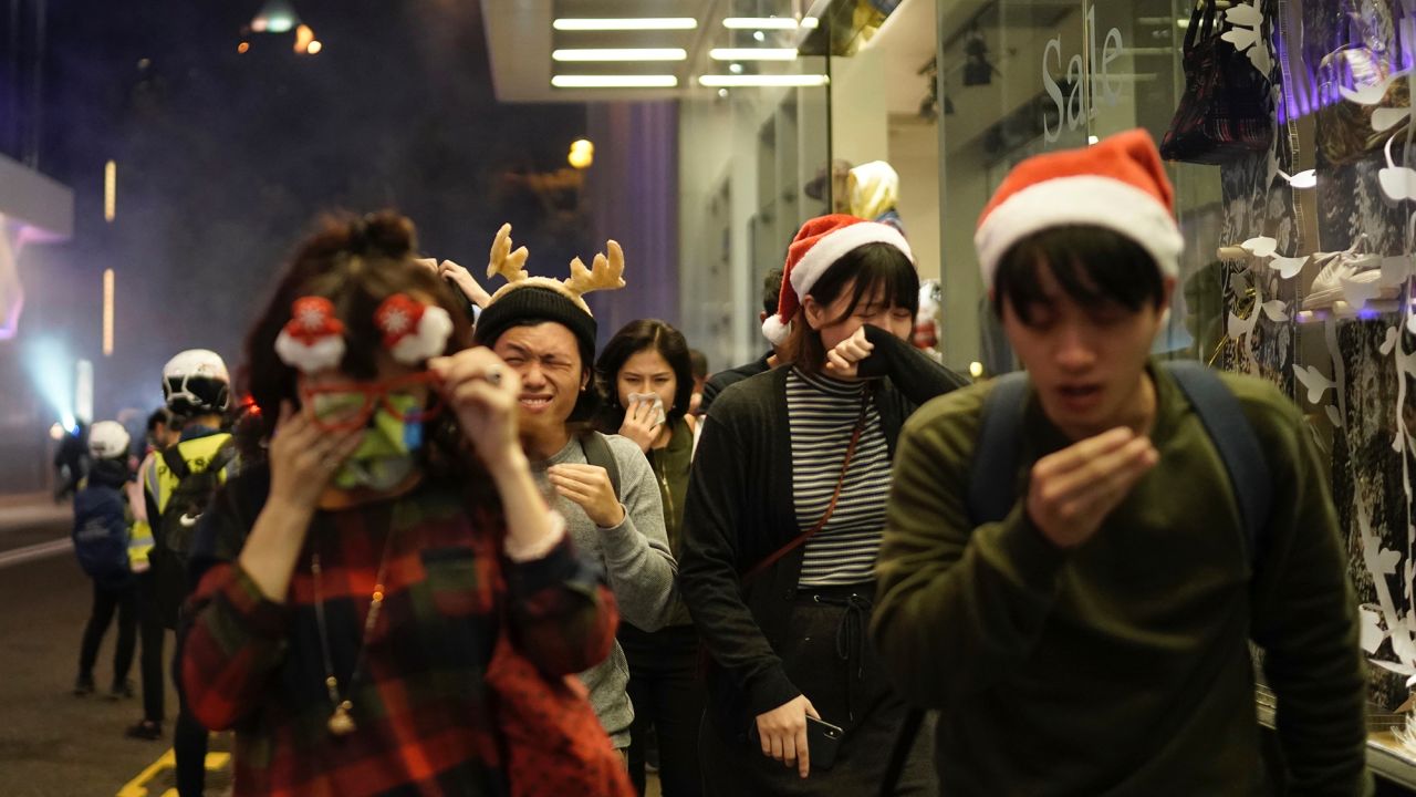 Residents dressed for Christmas festivities react to tear gas as police confront protesters on Christmas Eve in Hong Kong.