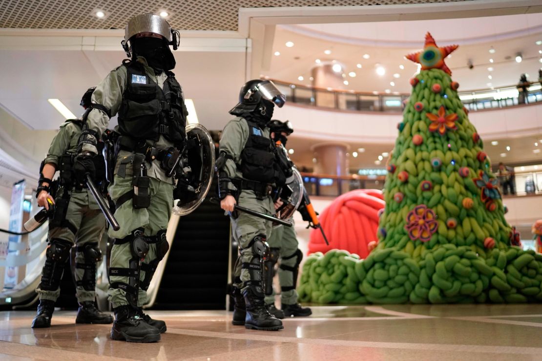 Riot police pass by Christmas decor in a shopping mall during a protest rally on Christmas Eve.