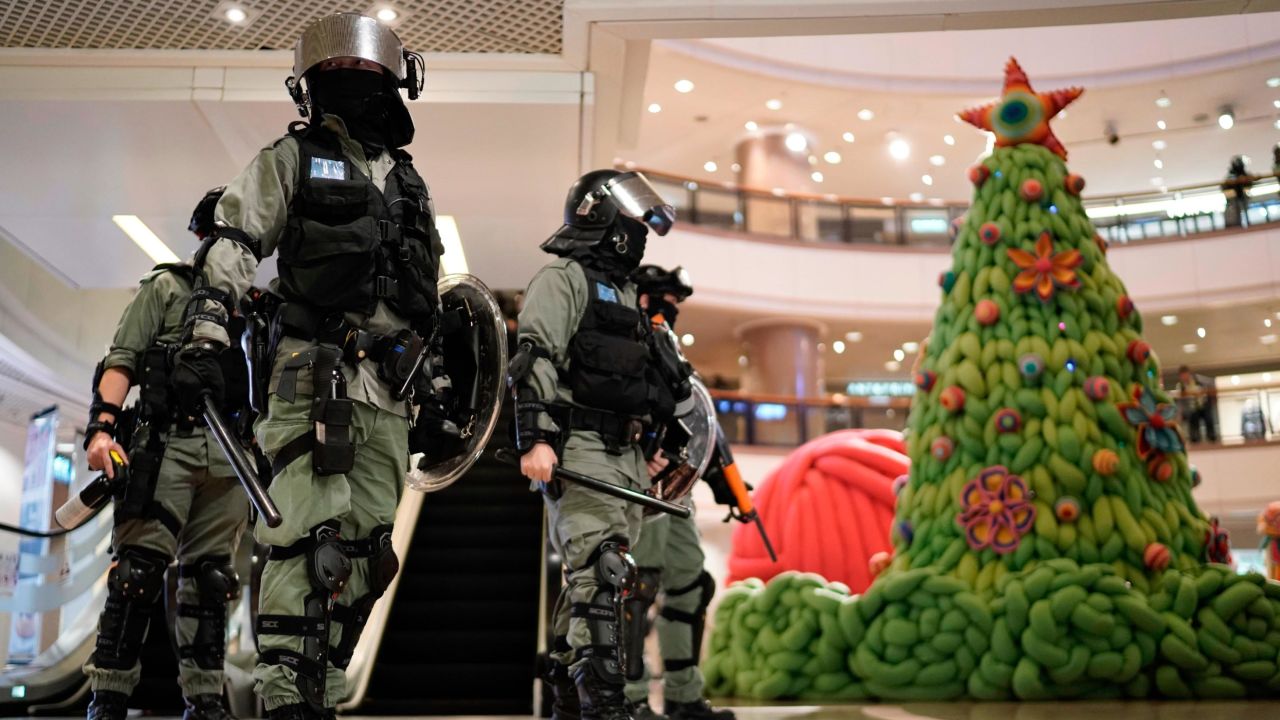 Riot police pass by Christmas decor in a shopping mall during a protest rally on Christmas Eve.