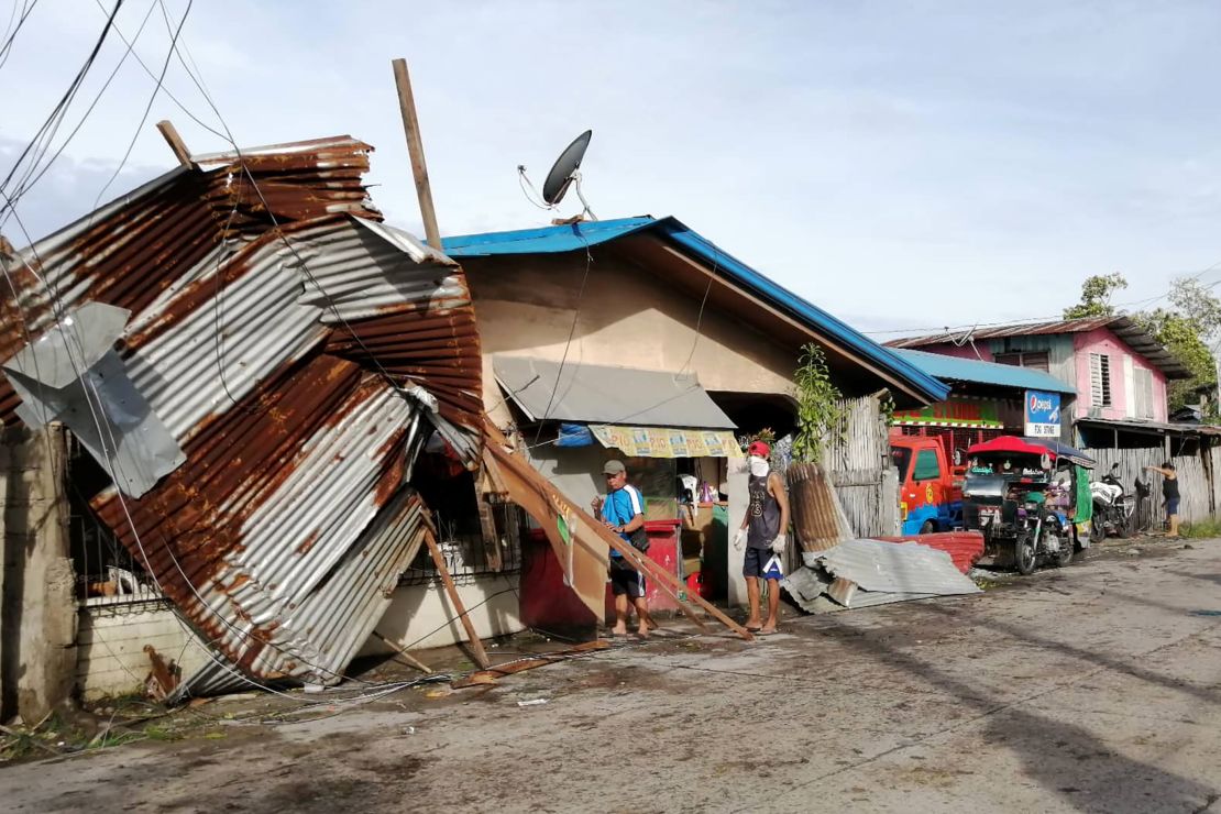 Residents stand next to a house damaged by typhoon Phanfone in Ormoc City, Leyte province in central Philippines.