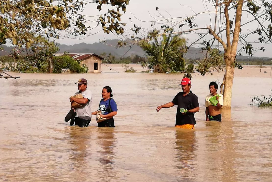 People in Leyte province wade through a flooded highway, caused by heavy rains due to typhoon Phanfone, in Ormoc city.