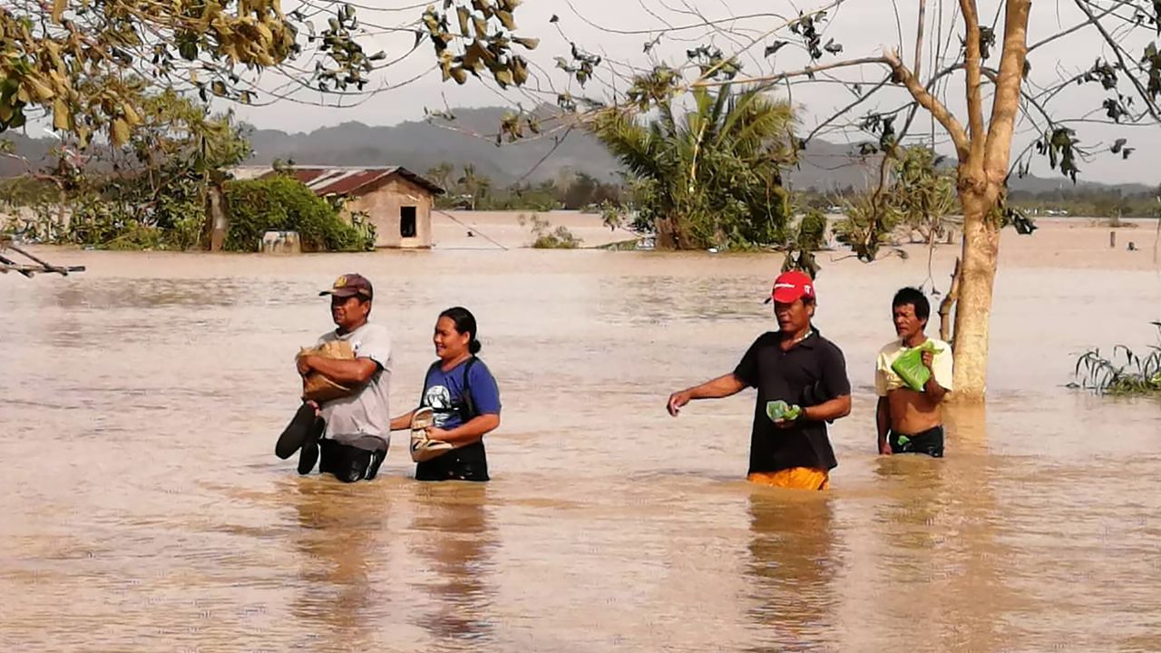 People in Leyte province wade through a flooded highway, caused by heavy rains due to typhoon Phanfone, in Ormoc city.