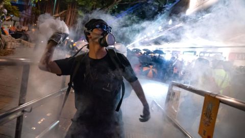 HONG KONG, CHINA - AUGUST 11: A protester throws back tear gas fired by riot police in the Cheung Sha Wan area on August 11, 2019 in Hong Kong, China. Pro-democracy protesters have continued rallies against a controversial extradition bill since June 9, when the city was plunged into crisis after waves of demonstrations and several violent clashes. While Hong Kong's Chief Executive Carrie Lam apologized for introducing the bill and declared it "dead," protests have continued to draw large crowds with demands for Lam's resignation and a complete withdrawal of the bill. (Photo by Billy H.C. Kwok/Getty Images)