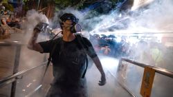 HONG KONG, CHINA - AUGUST 11:  A protester throws back tear gas fired by riot police in the Cheung Sha Wan area on August 11, 2019 in Hong Kong, China. Pro-democracy protesters have continued rallies against a controversial extradition bill since June 9, when the city was plunged into crisis after waves of demonstrations and several violent clashes. While Hong Kong's Chief Executive Carrie Lam apologized for introducing the bill and declared it "dead," protests have continued to draw large crowds with demands for Lam's resignation and a complete withdrawal of the bill. (Photo by Billy H.C. Kwok/Getty Images)