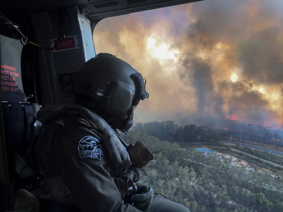 A member of the Australian Defence Force overlooking the bushfires in New South Wales on board a helicopter. 
