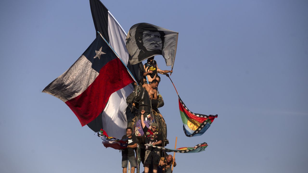 Demonstrators wave Chilean and Mapuche flags during a protest against the government of Chilean President Sebastian Pinera in Santiago, on December 27, 2019. - Chile has been rocked by months of protests that began with strikes over metro fare hikes and quickly escalated into the most severe outbreak of social unrest since the end of the dictatorship of Augusto Pinochet nearly 30 years ago. (Photo by CLAUDIO REYES / AFP) (Photo by CLAUDIO REYES/AFP via Getty Images)