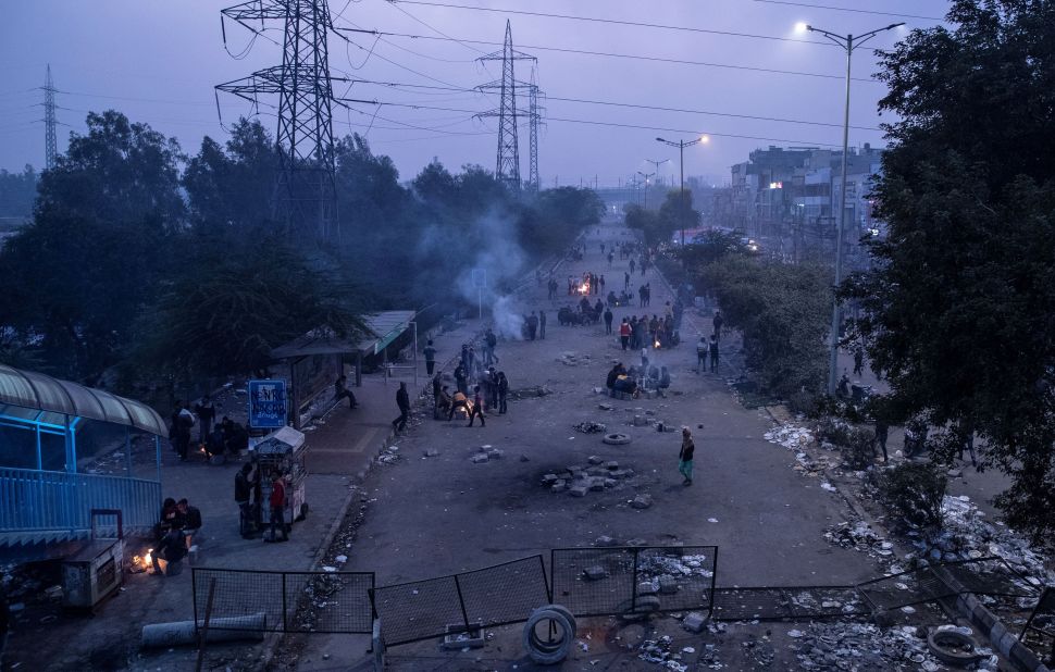 Demonstrators sit next to bonfires during dusk as they block a road during a protest in New Delhi on Sunday, December 22.