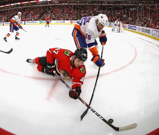 Chicago Blackhawks' John Quenneville tries to knock the puck away from Johnny Boychuk of the New York Islanders on Friday, December 27, in Chicago.