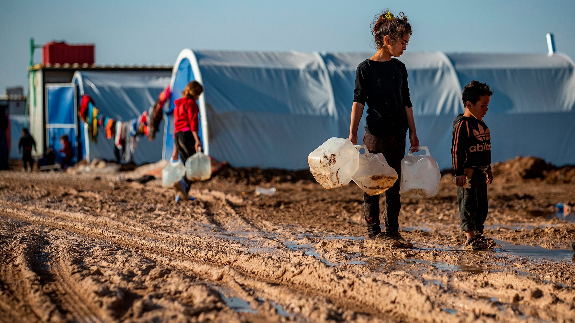 Children carry jugs to fill with water in the Washukanni camp for internally displaced people in northeastern Syria.