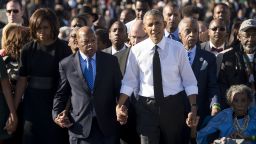 US President Barack Obama walks alongside Amelia Boynton Robinson (R), one of the original marchers, the Reverend Al Sharpton (2nd R), First Lady Michelle Obama (L), and US Representative John Lewis (2nd-L), Democrat of Georgia, and also one of the original marchers, across the Edmund Pettus Bridge to mark the 50th Anniversary of the Selma to Montgomery civil rights marches in Selma, Alabama, March 7, 2015. The event commemorates Bloody Sunday, when civil rights marchers attempting to walk to the Alabama capital of Montgomery to end voting discrimination against African Americans, clashed with police on the bridge. AFP PHOTO / SAUL LOEB        (Photo credit should read SAUL LOEB/AFP via Getty Images)
