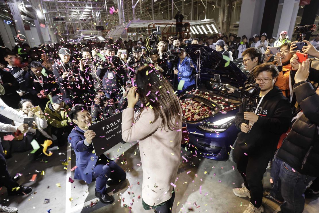 An employee, left, proposes to his girlfriend with his newly delivered Tesla Model 3 in Shanghai on Monday.