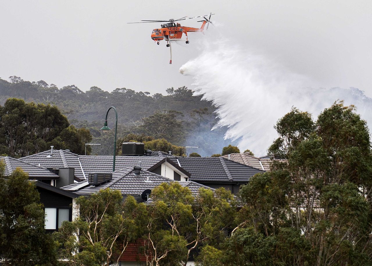 A skycrane drops water on a bushfire burning near houses in Bundoora, Melbourne, on Monday, December 30.