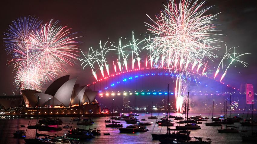 New Year's Eve fireworks erupt over Sydney's iconic Harbour Bridge and Opera House (L) during the fireworks show on January 1, 2020.