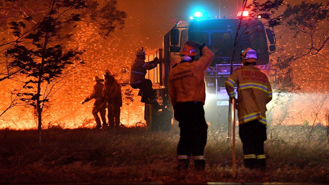 Firefighters hose down trees as they battle against bushfires around the town of Nowra in the Australian state of New South Wales on December 31, 2019. Thousands of holidaymakers and locals were forced to flee to beaches in fire-ravaged southeast Australia on December 31, as blazes ripped through popular tourist areas leaving no escape by land.