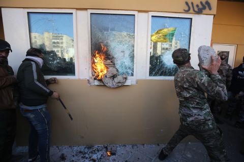Protesters and militia fighters smash the bullet-proof glass of the embassy's windows with blocks of cement after breaching the outer wall.