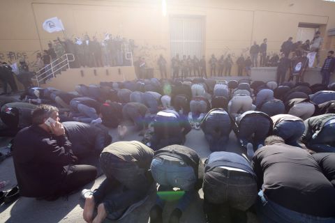 Iraqi security forces stand guard as protesters, including clerics, hold a prayer inside the walls of the embassy.