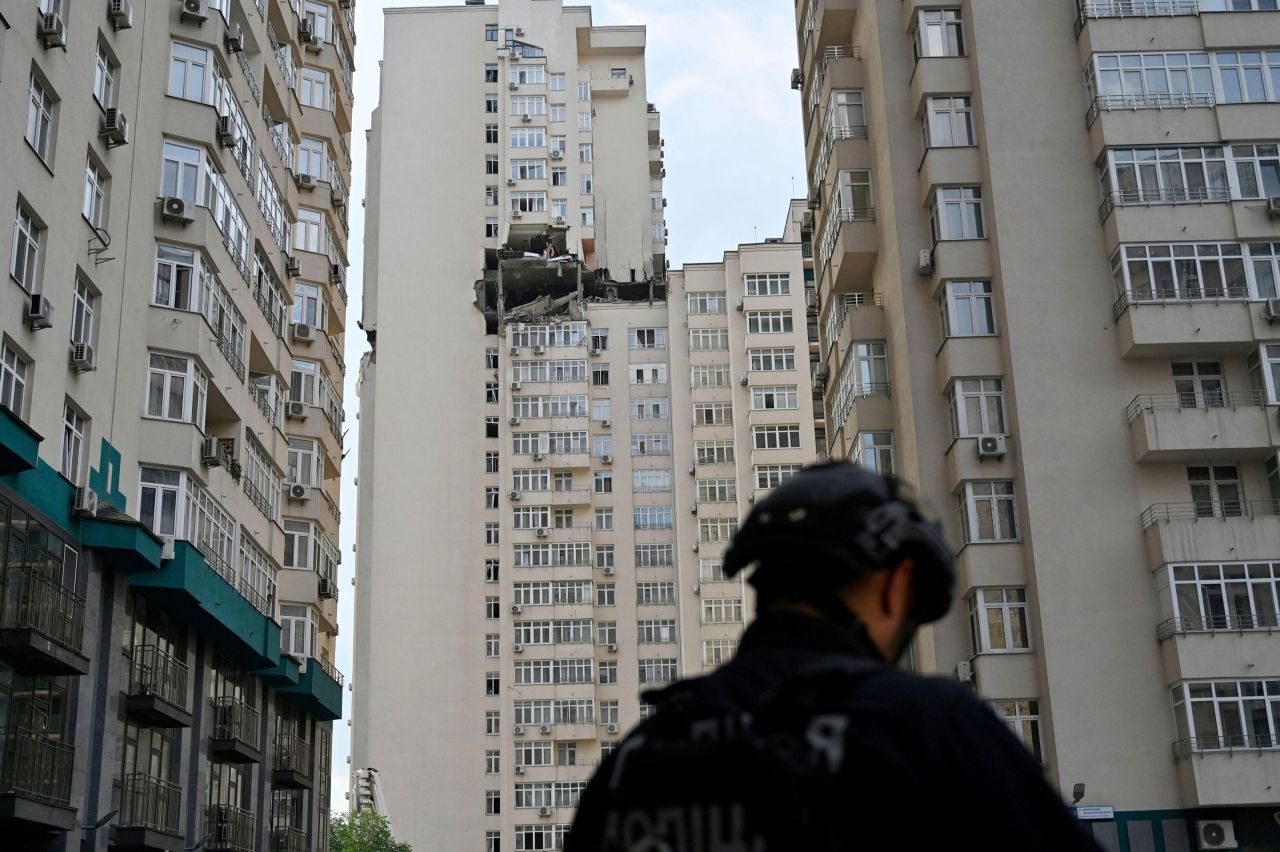 A policeman stands near a residential building damaged from a missile attack in Kyiv, on June, 24.