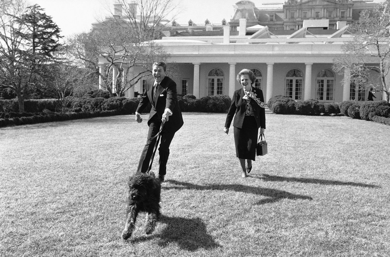 President Ronald Reagan is pulled along by his pet dog Lucky while he and British Prime Minister Margaret Thatcher take a stroll in the Rose Garden in February 1985.