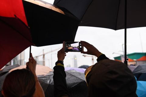 Protesters take photos as they shelter from the rain. 