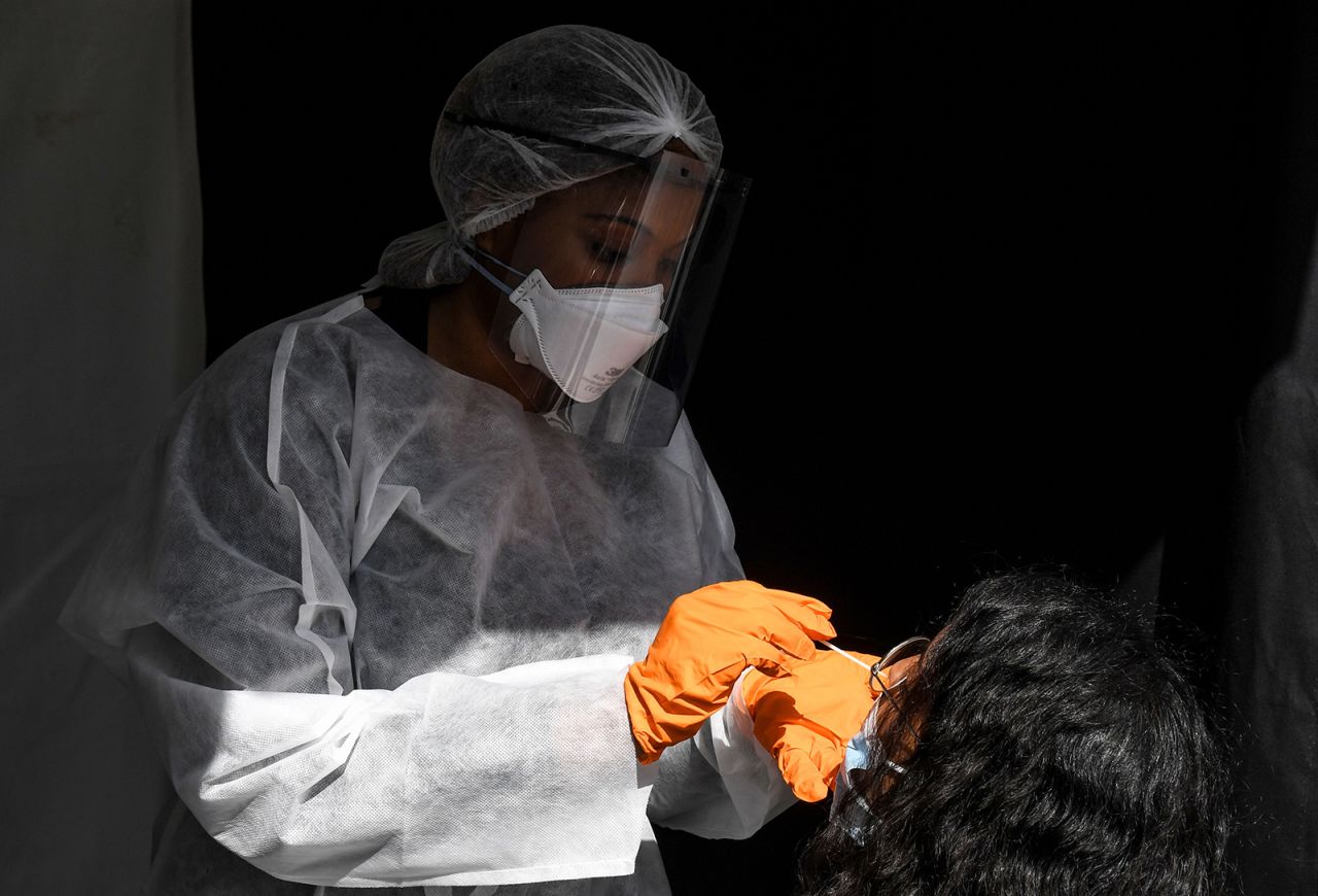 A medical worker wearing protective equipment uses a swab to do a PCR test for Covid-19 on a woman wearing a face mask in front of the city hall of Paris on August 31.