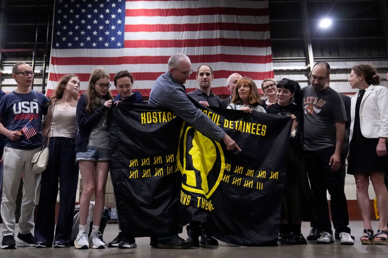 Paul Whelan points to tally marks on a Hostage and Wrongful Detainee flag while standing with other recently freed Americans and their families at Kelly Field in San Antonio, Texas, on Friday.