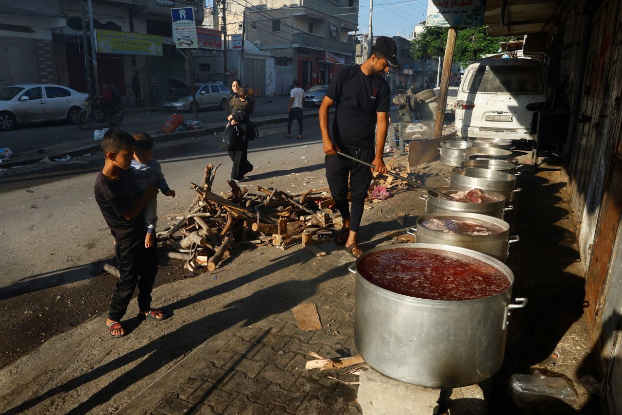 People cook on firewood amid shortages of fuel and gas to provide food for Palestinians who fled their houses amid?Israeli strikes in Khan Younis, southern Gaza, on October 15, 2023.