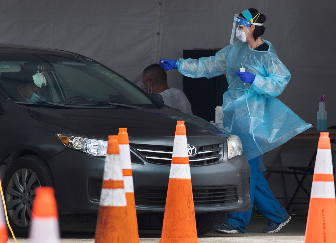 A healthcare worker tests a person for Covid-19 at the test site located in the Hard Rock Stadium parking lot on July 13, in Miami Gardens, Florida. 