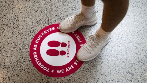 A student stands on a socially distancing marker while waiting in line inside the Thompson Library on the first day of classes at Ohio State University in Columbus, Ohio, on August 25.