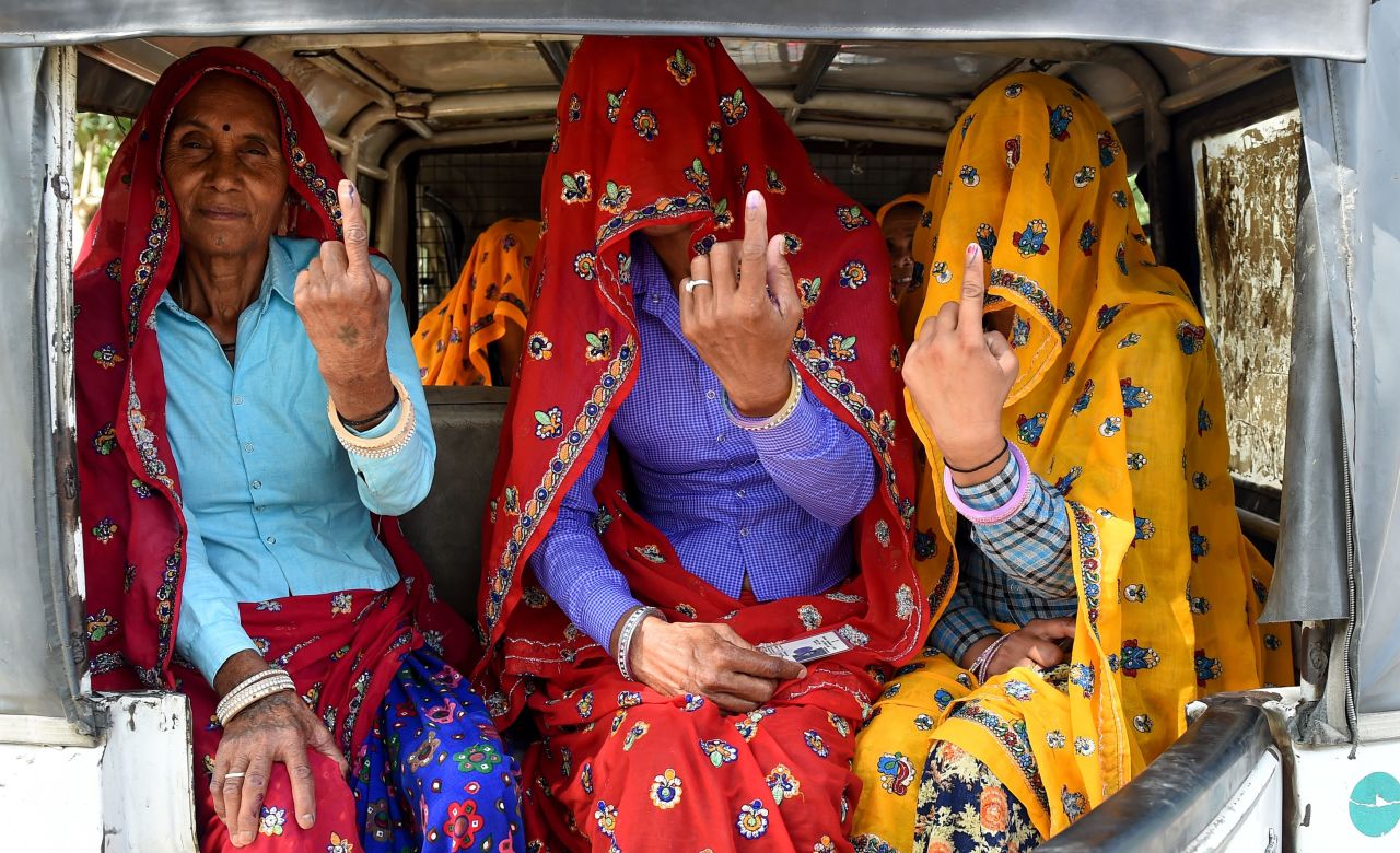 Indian women sit inside an auto-rickshaw as they show their ink-marked fingers after casting their vote in Alwar in the northern Indian state of Rajasthan on May 6, 2019. 