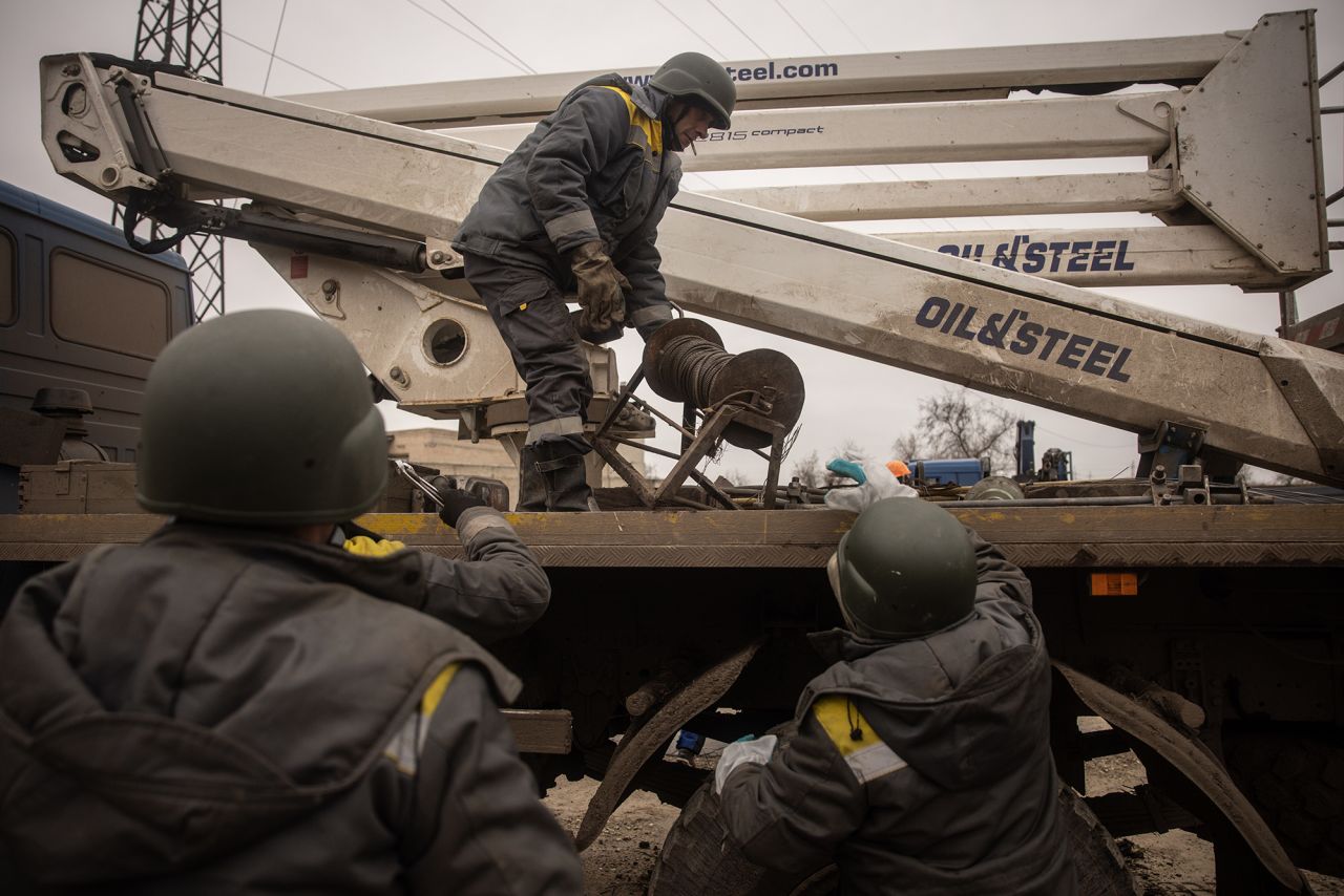 Electricity workers wearing bulletproof vests and helmets prepare to start work to repair a destroyed high voltage power line on December 1, in Kherson, Ukraine.