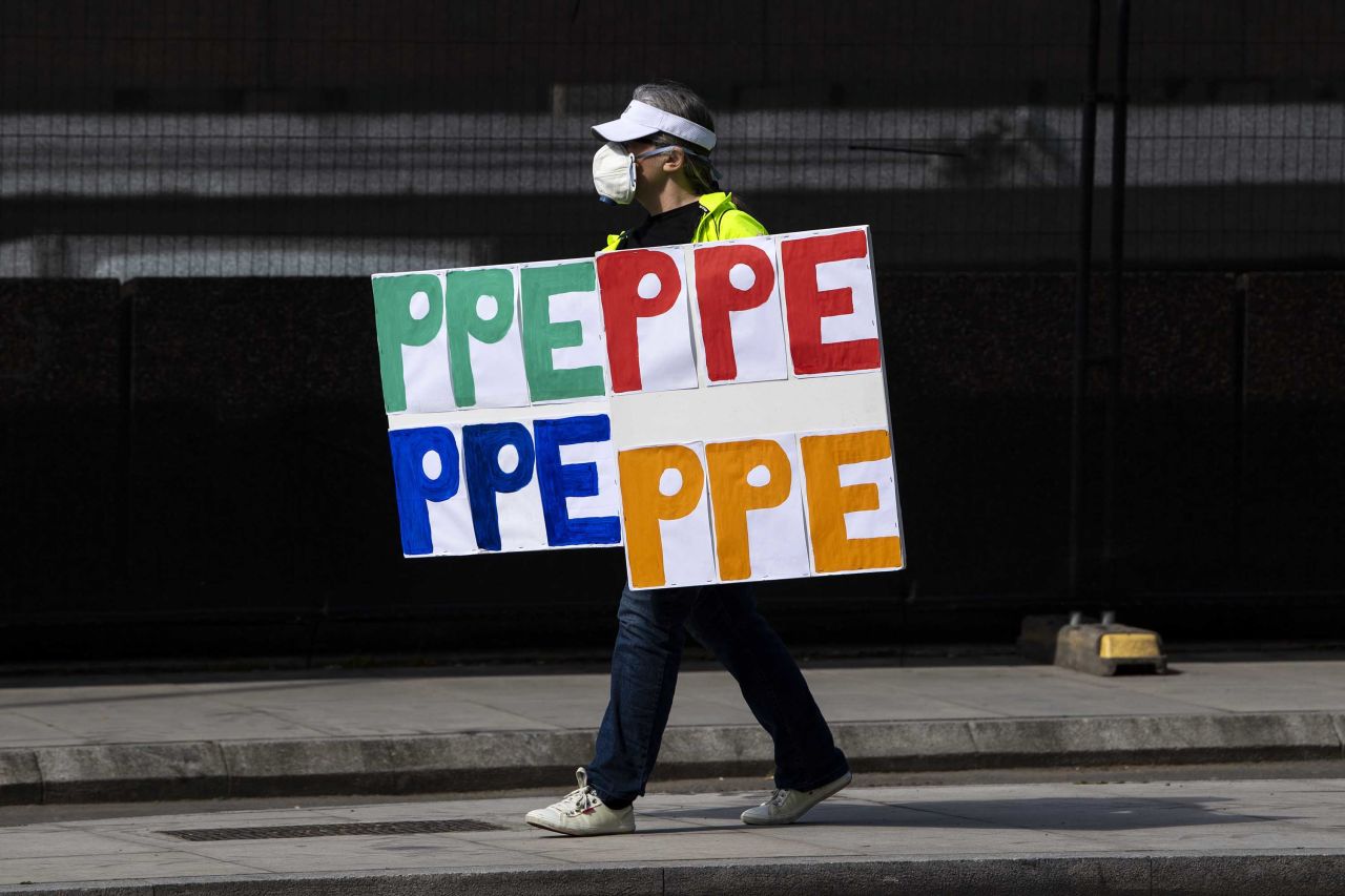 A person wearing a face mask holds up a banner reading: 'PPE' outside St Thomas' Hospital on April 07, 2020 in London, England. (Photo by Justin Setterfield/Getty Images)