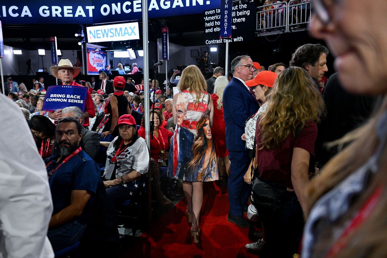 A woman with a dress featuring a photo of former President Donald Trump and Melania walks through the 2024 Republican National Convention.