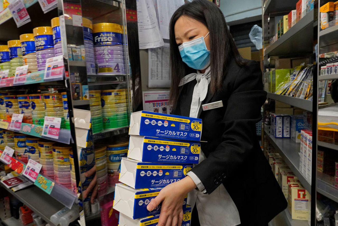 An employee carries boxes of face masks as people queue up to buy face masks at a cosmetics shop in Hong Kong, Thursday, January, 30. The masks in the photo were not part of the seizure. 