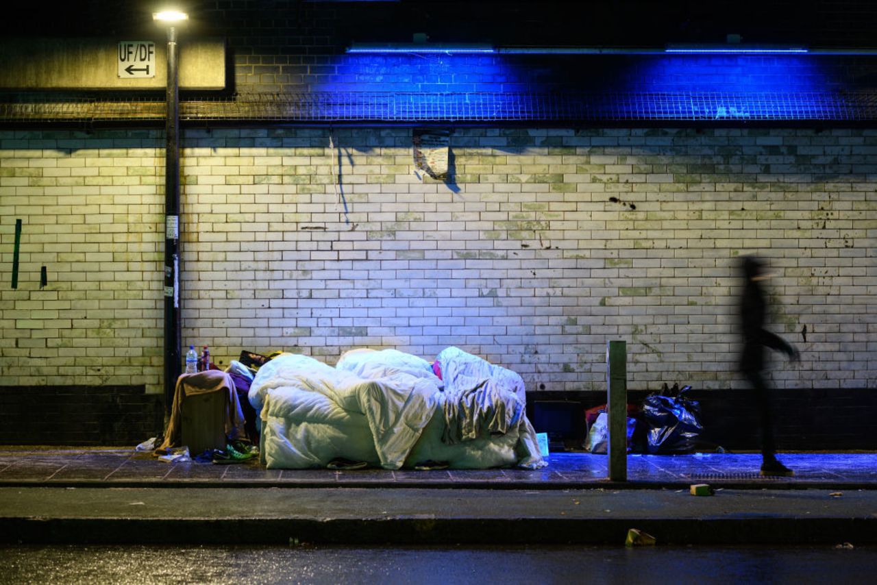 A commuter walks past three homeless people in London.