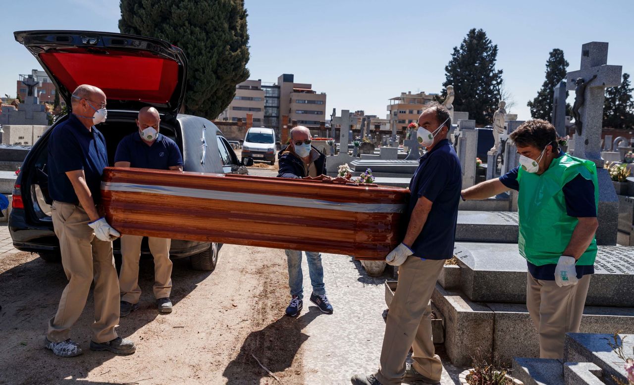 Mortuary employees carry the coffin of a coronavirus victim during a burial at the Fuencarral cemetery in Madrid, on March 29.