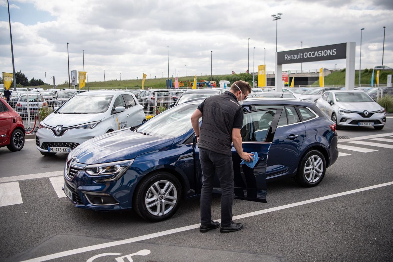 An employee wearing a protective face mask disinfects the exterior of a new automobile for a customer at a Renault SA showroom in Lille, France, on Tuesday, May 12. 