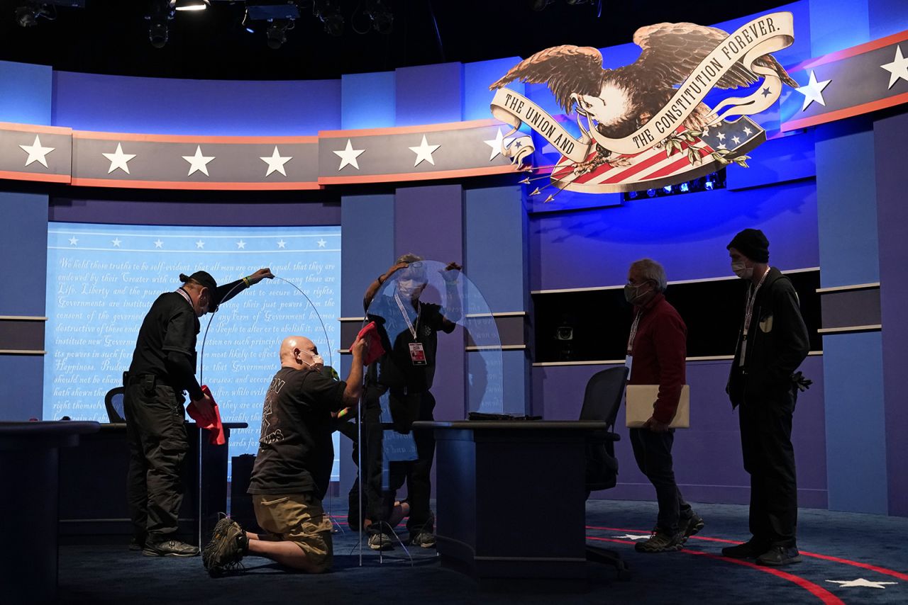 Workers clean protective plastic panels onstage between tables for Vice President Mike Pence and Democratic vice presidential candidate, Sen. Kamala Harris, as preparations take place for the vice presidential debate at the University of Utah on Tuesday in Salt Lake City.