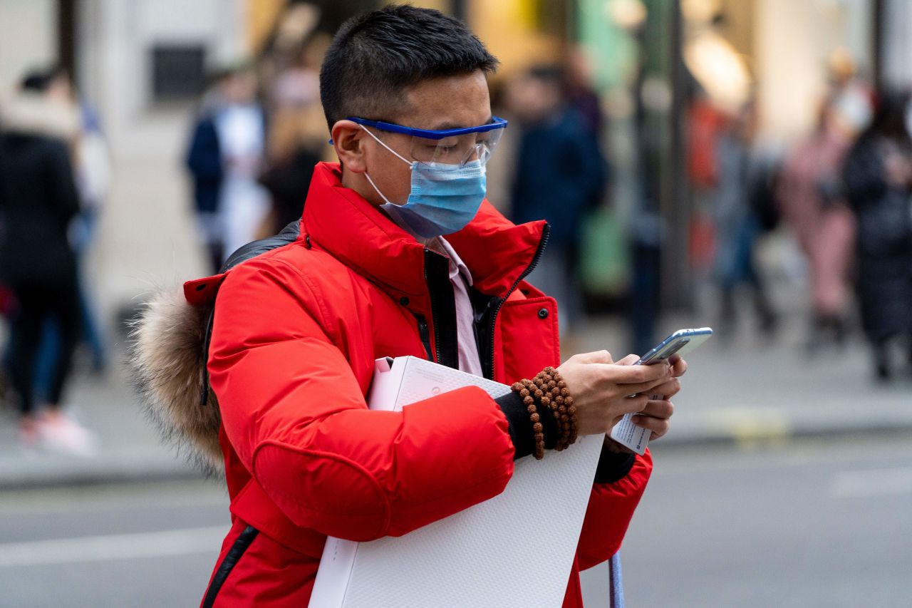 A pedestrian wears a surgical mask as he checks his phone while walking along London's Regent Street in central London on Jan. 25. European airports from London to Moscow stepped up checks Wednesday on flights from the Chinese city at the heart of the coronavirus that has killed 41 people and spread to the United States.