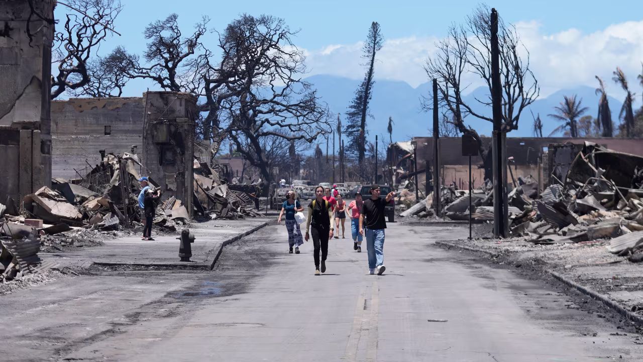 People walk along Main Street past wildfire damage on August 11, 2023, in Lahaina, Hawaii.