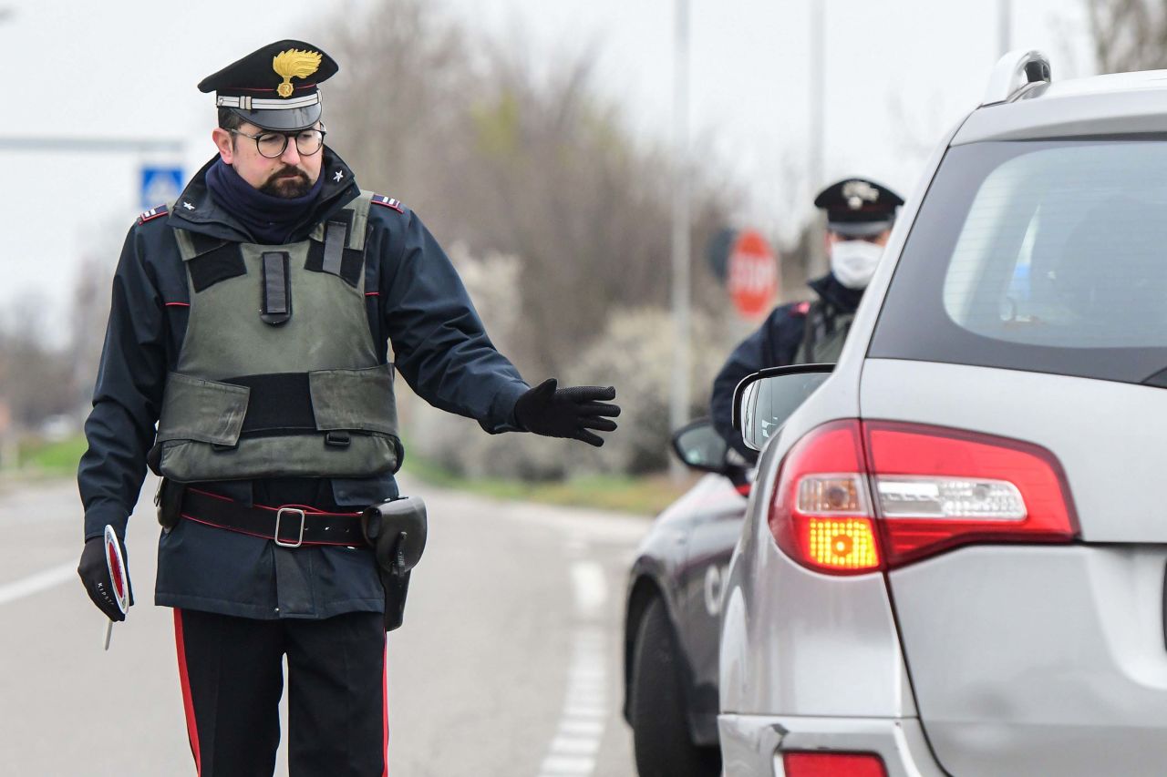 Italian Carabinieri police officers stop cars at a check point on the border between the quarantined provinces of Modena and Bologna in Valsamoggia, Italy, on Monday.