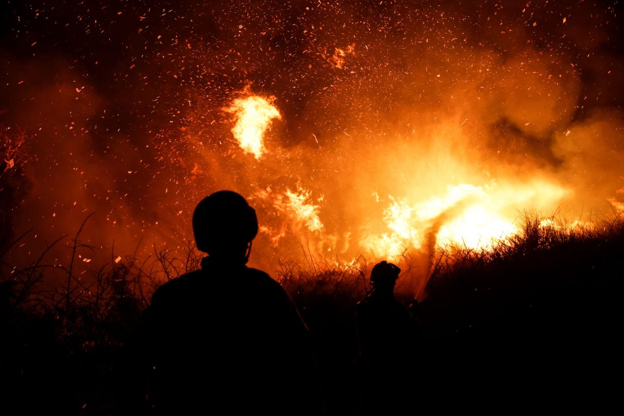 Firefighters work to put out a fire in an open field, following a mass-infiltration by Hamas gunmen from Gaza, near a hospital in Ashkelon, southern Israel, on October 7, 2023.