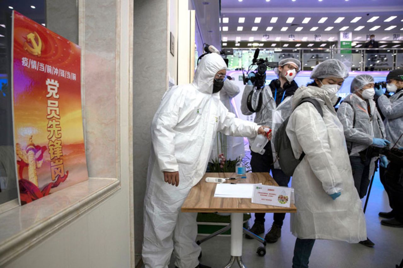 A worker disinfects journalists visiting the Mengniu dairy factory in Beijing on Thursday, February 27. 