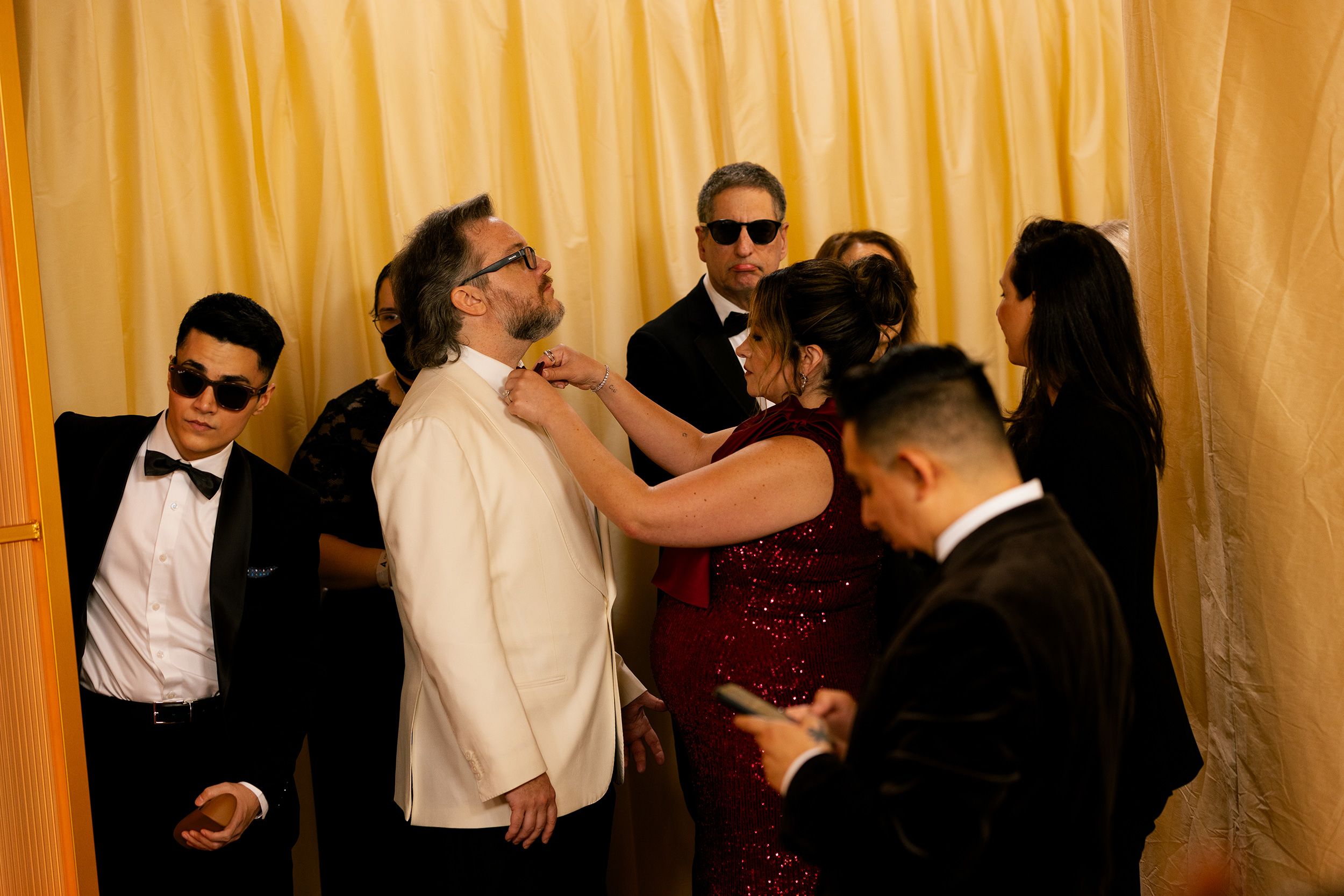 An attendee's bowtie is adjusted before walking the red carpet.