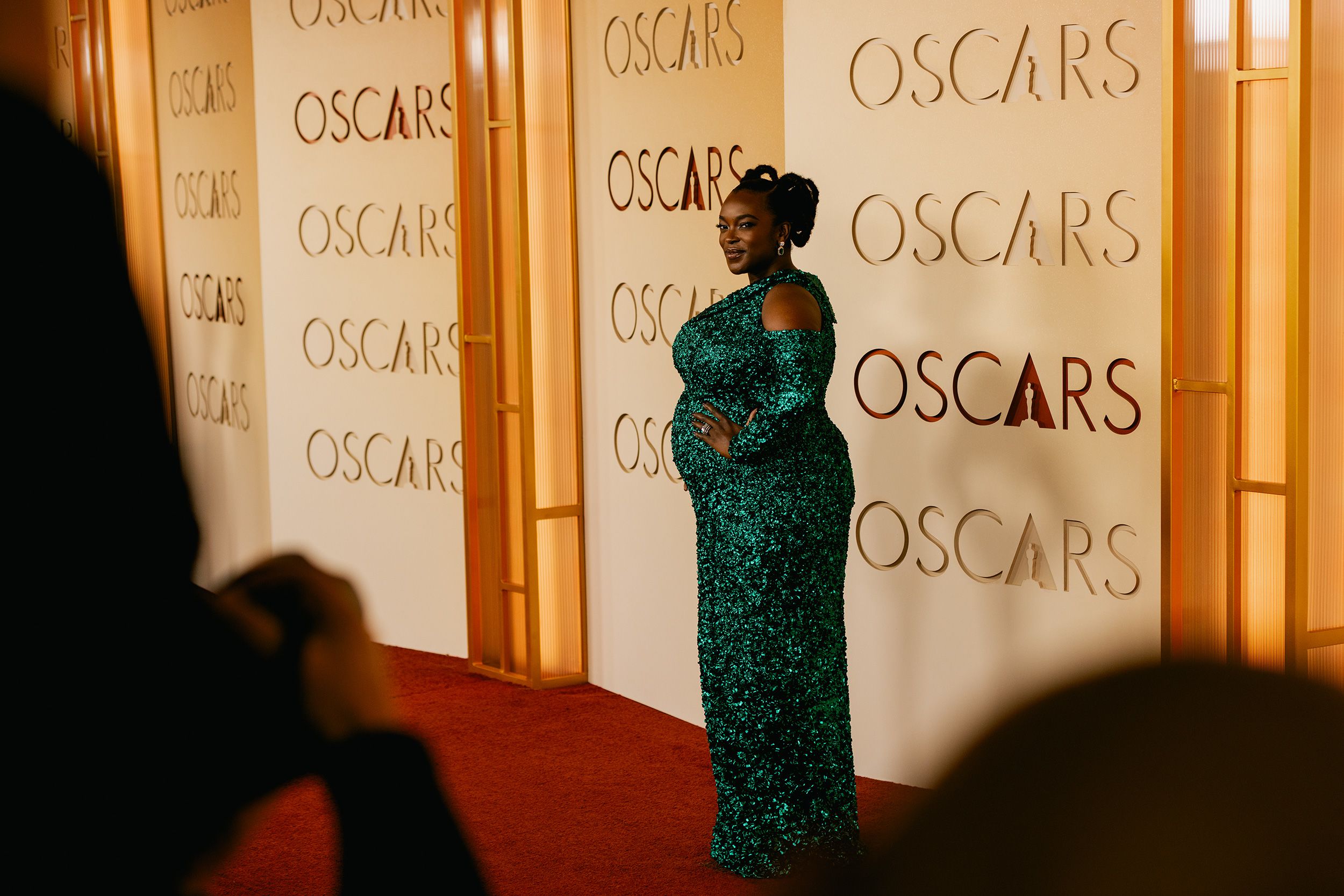 Wunmi Mosaku, baby bump on full display, in a sparkling green hand-embroidered Louis Vuitton gown.