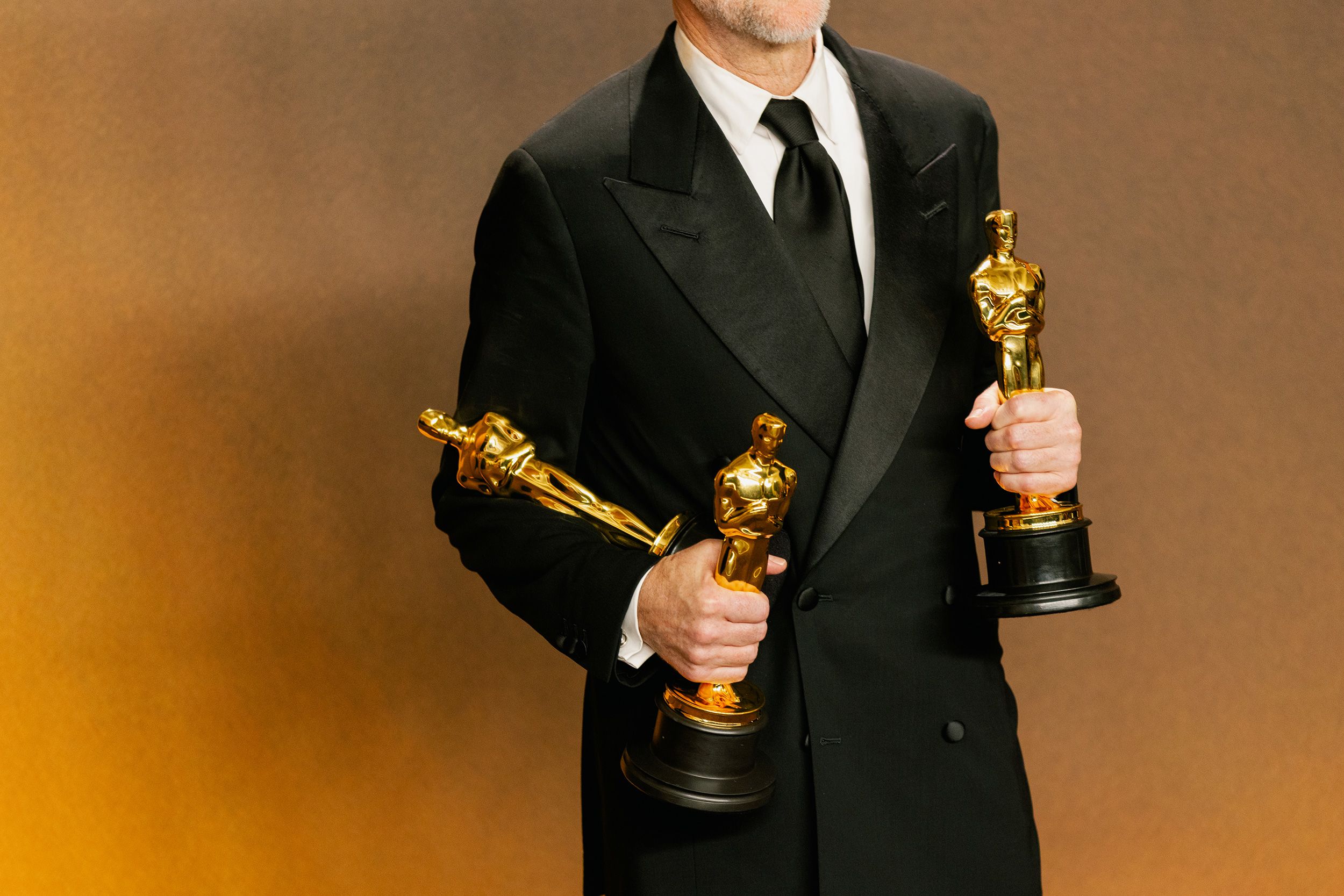 Paul Thomas Anderson holds his awards — three of the six won by “One Battle After Another” — backstage.