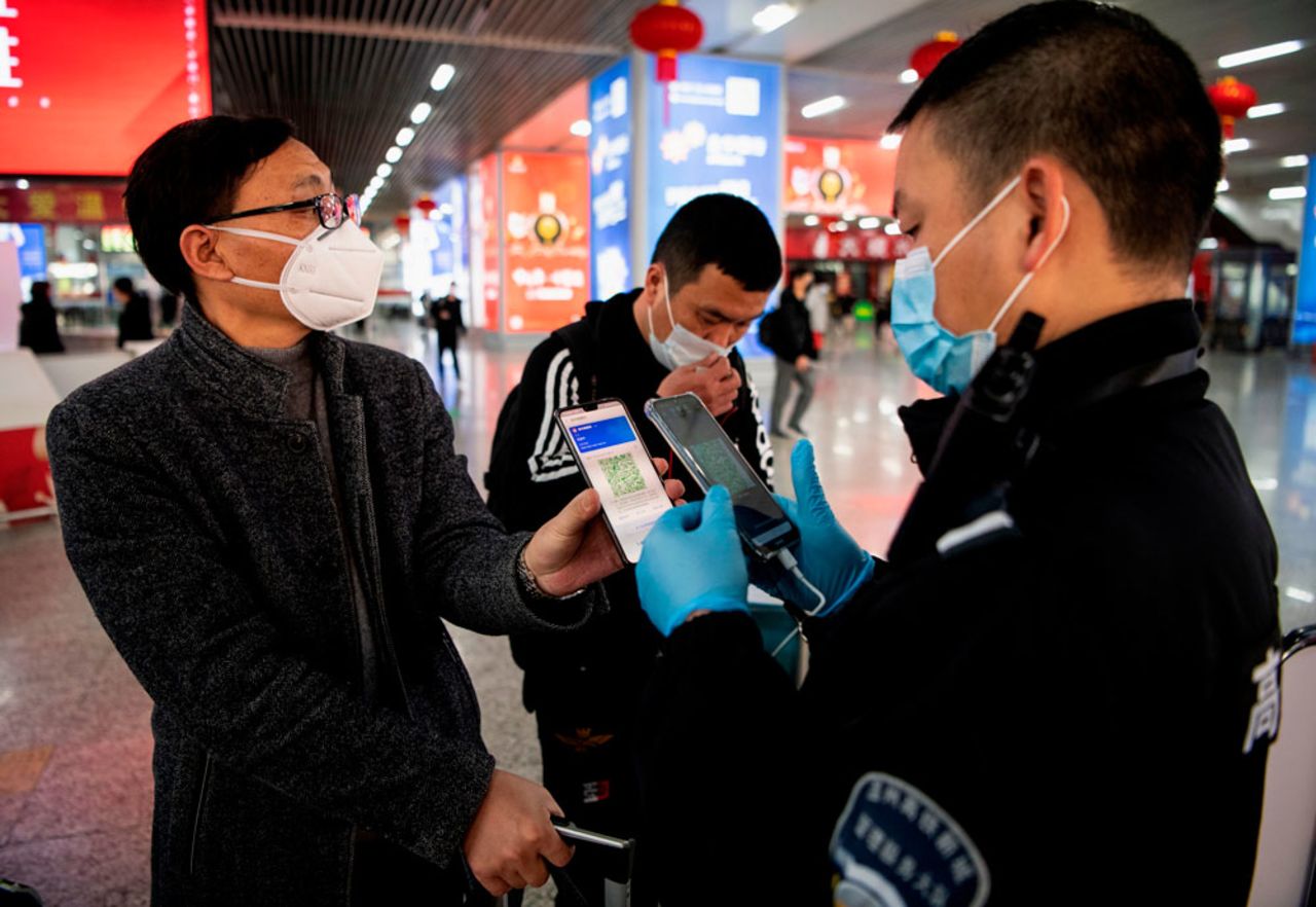 A passenger shows a green QR code on his phone to a security guard to indicate his health status at Wenzhou railway station in China on February 28.