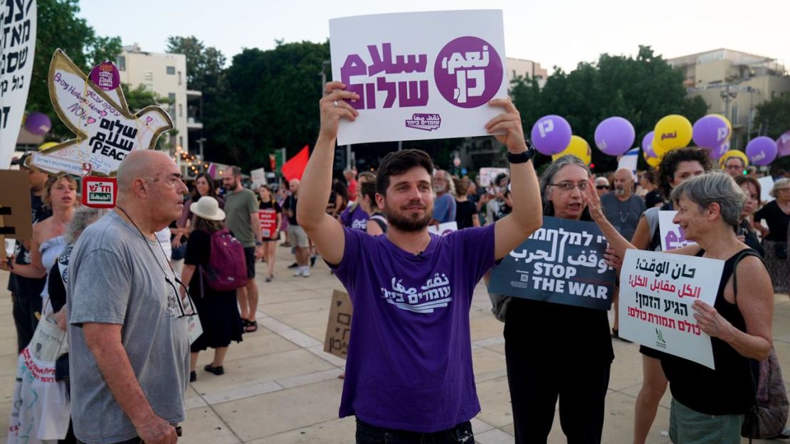 Michael Ofer Ziv carries a sign that says 'Peace' in Arabic and Hebrew, calling for a ceasefire and hostage deal at a protest in Tel Aviv.