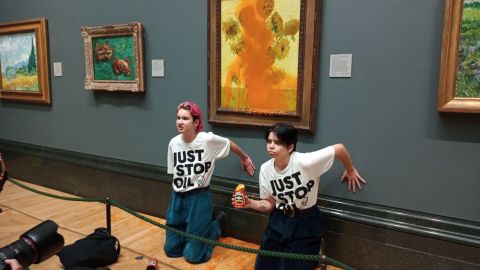 Two Just Stop Oil protesters sitting on the floor after they have thrown tinned soup at Vincent Van Gogh's famous 1888 work Sunflowers at the National Gallery in London on October 14, 2022.
