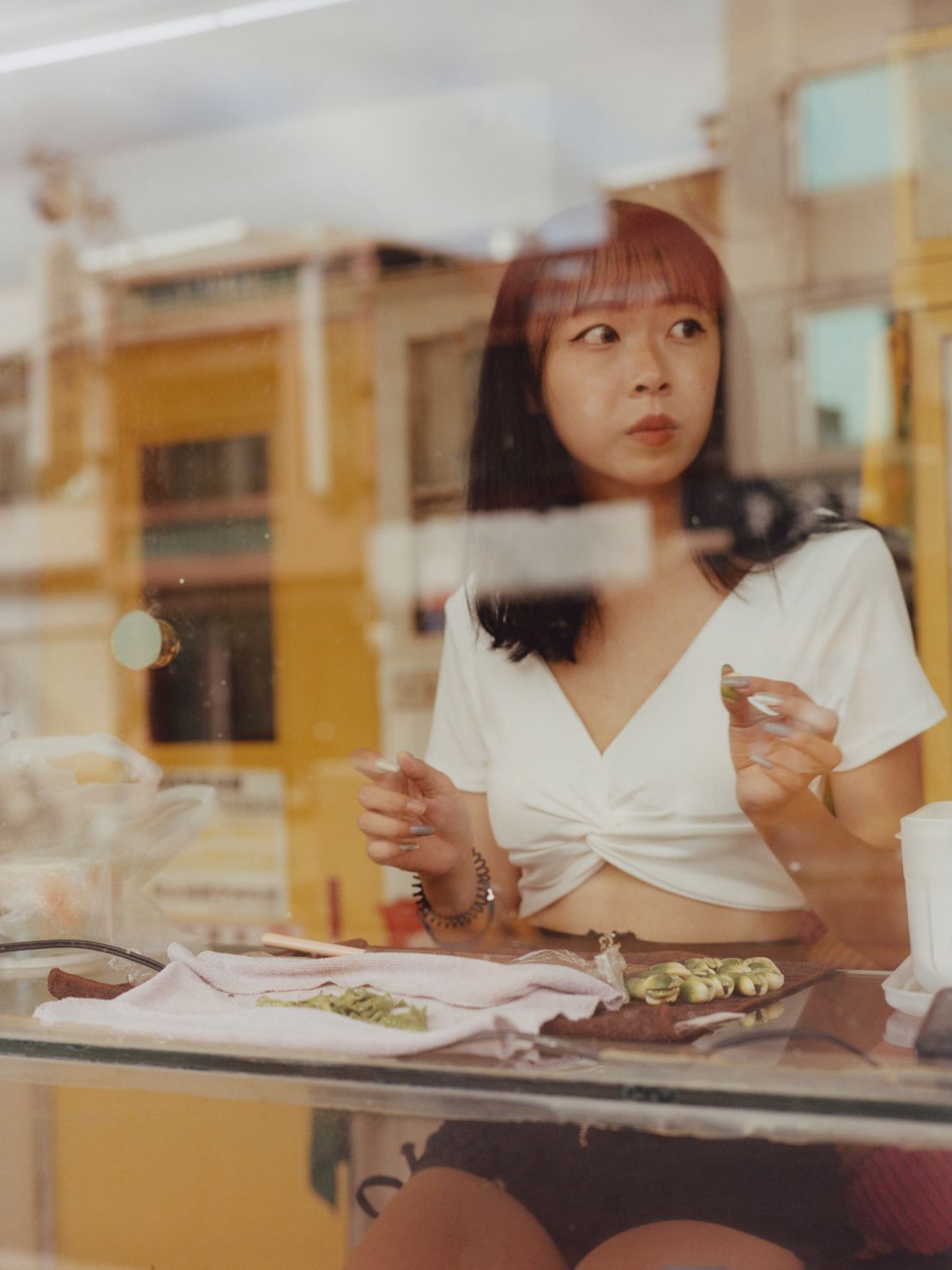 A seller looks for customers while she prepares betel nuts.